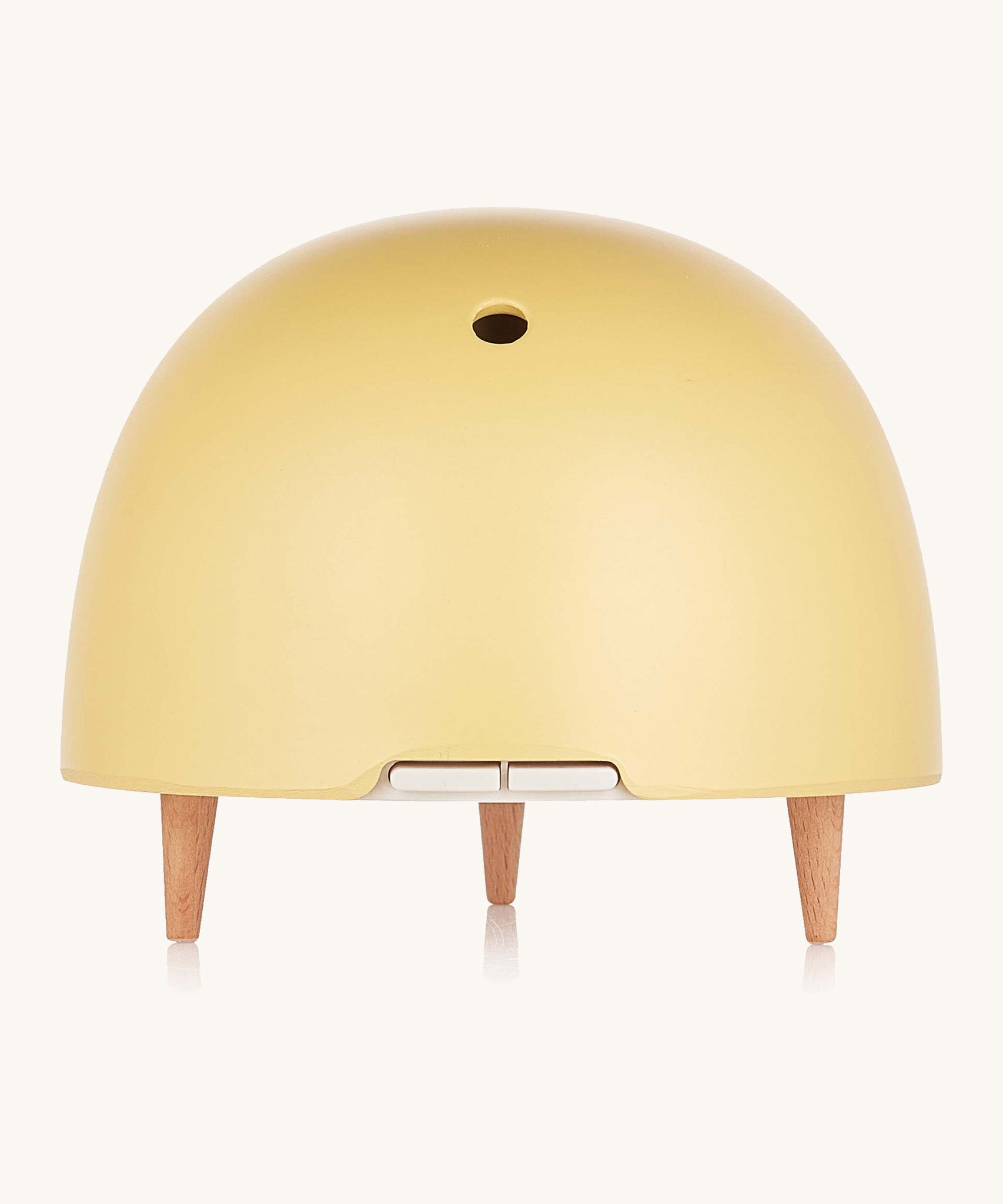 Maël Diffuser, a light yellow dome plug-in essential oil diffuser with wooden feet. 