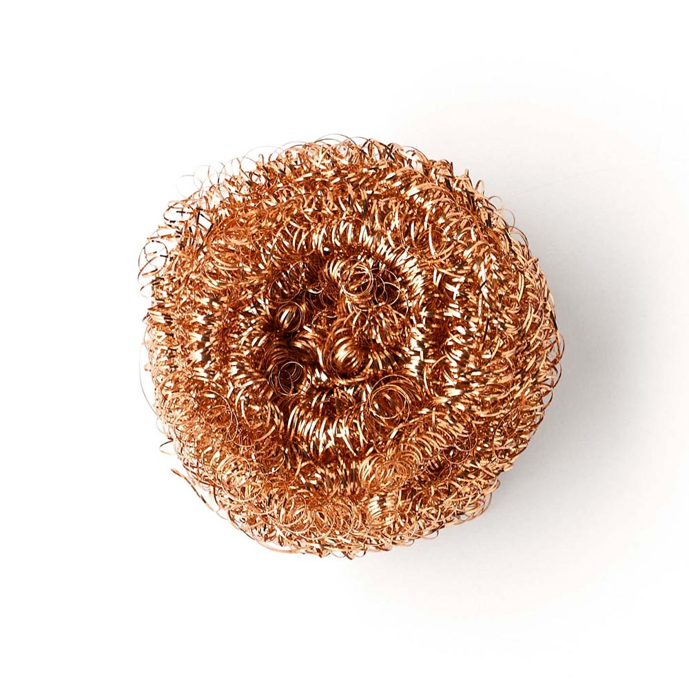 Close up of a Seep recyclable copper dishwashing scourer on a white background