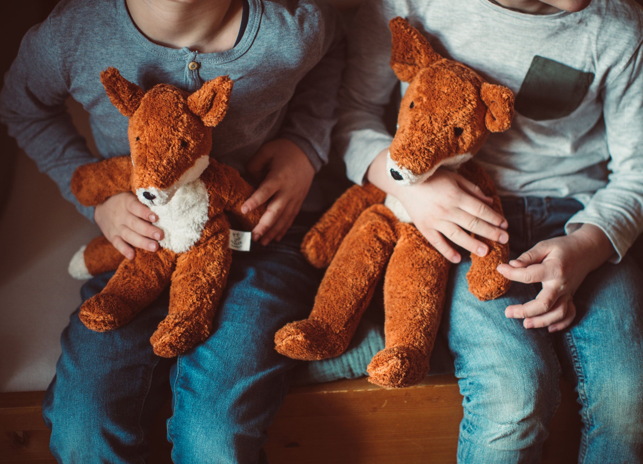 A close up of two children's hands holding Senger Floppy Foxes.