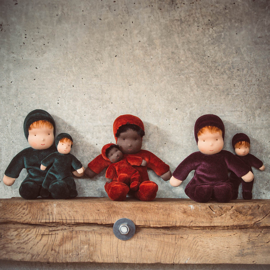 A child smiling happily and hugging the Senger Large Poppy Flower Doll in their arms