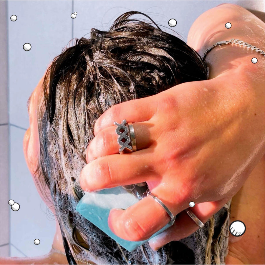 Woman applying a Shower Blocks solid natural shampoo and conditioner bar to her hair in the shower