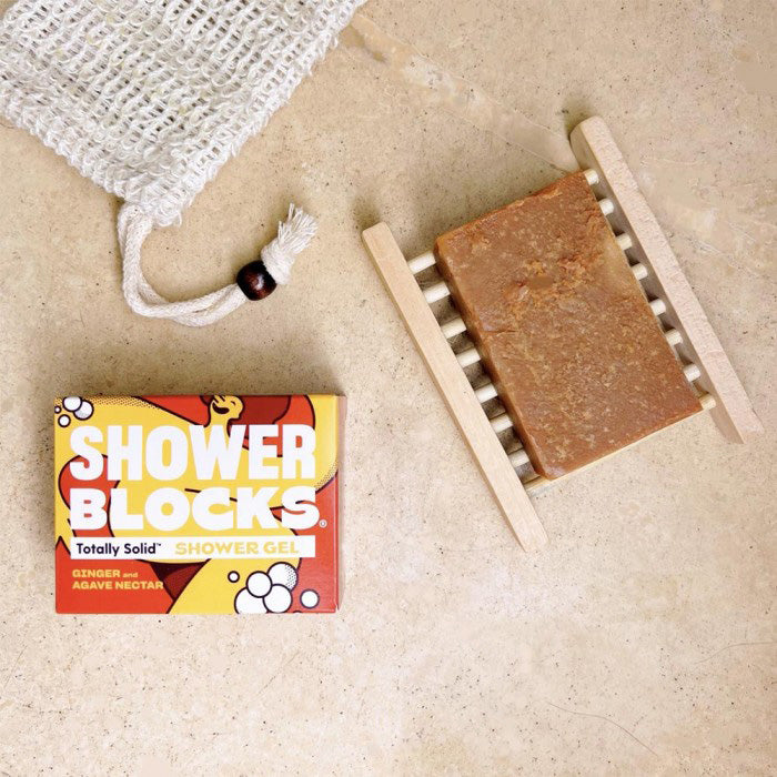 Shower Blocks Ginger & Agave Nectar Gel Bar pictured on a wooden soap holder alongside the packaging and a jute soap saver bag