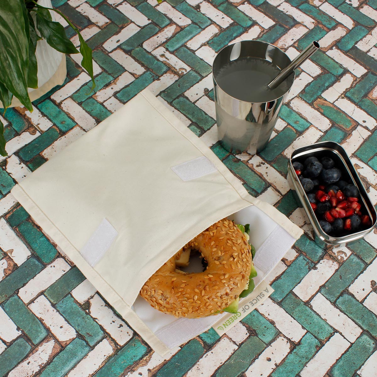 Stuffed bagel inside A Slice of Green large food baggie on some green and white tiles