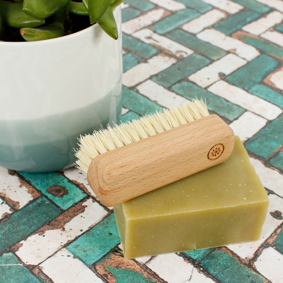 Close up of A Slice of Green plastic-free wooden nail brush on top of a green soap bar