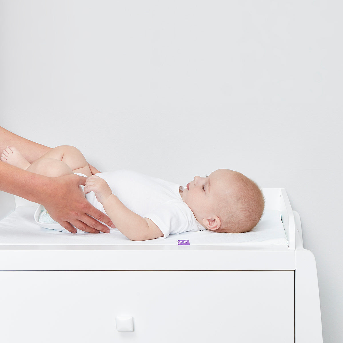 A close up of a baby laying on the top of a changing unit