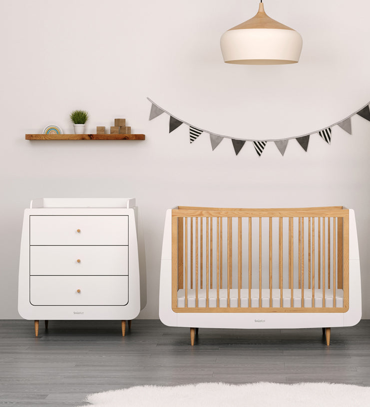 A natural SnuzKot changing unit pictured next to a matching cotbed