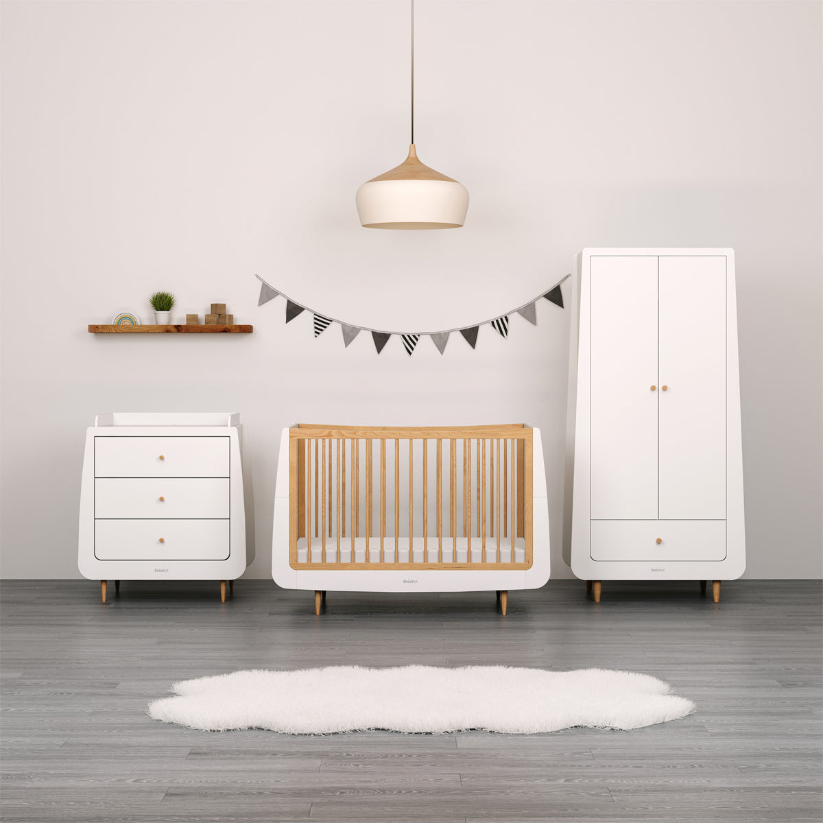 A collection of natural SnuzKot Furniture set up in a nursery. A changing unit, cot bed and a wardrobe can be seen in front of a light grey coloured wall