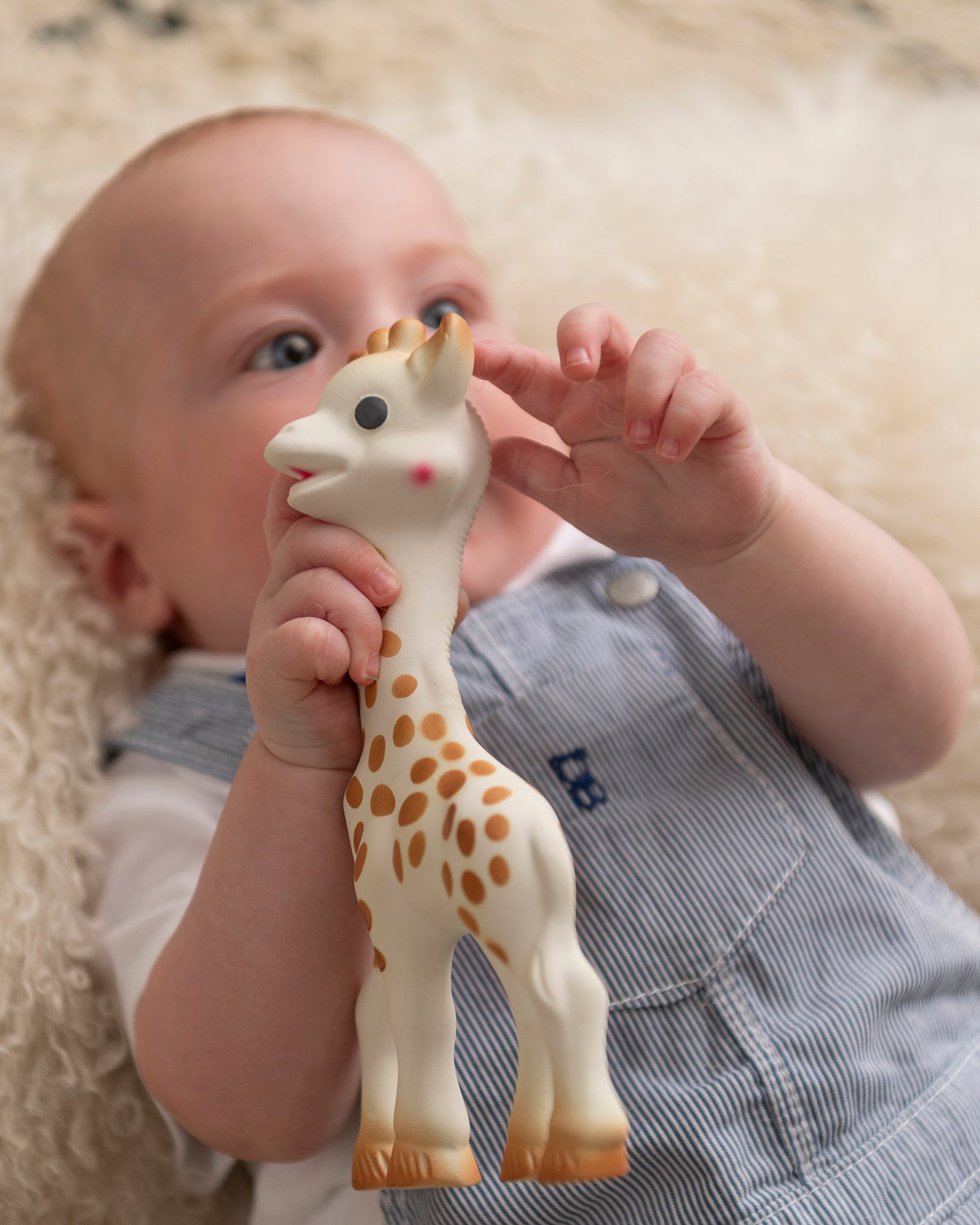 A baby happily grasping and chewing on the Sophie la Girafe® - Once Upon A Time 100% Natural Rubber Original Giraffe Teether