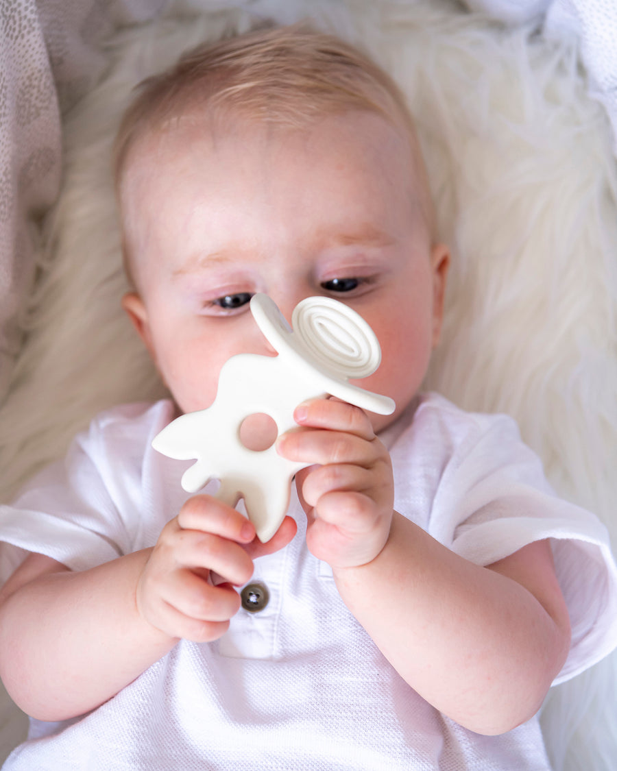  looking up and holding the Sophie la Girafe natural rubber teether