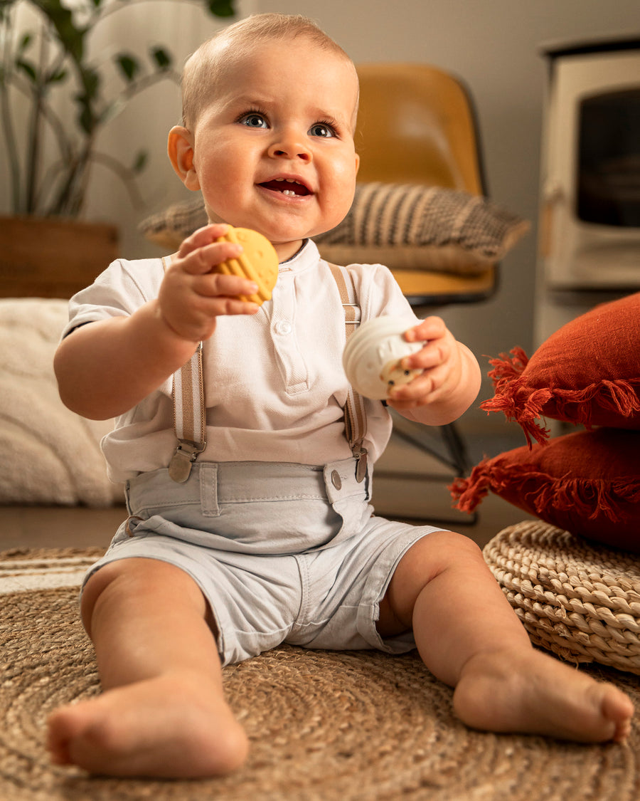 A child happily playing and holding the yellow and white musical balls from the Sophie The Giraffe - Once Upon A Time 5 Senses Musical Balls set