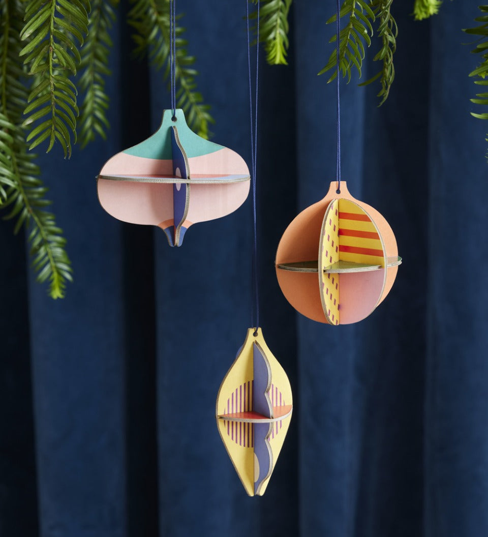 Studio Roof plastic-free hanging Christmas baubles hanging from a Christmas tree in front of a dark blue curtain