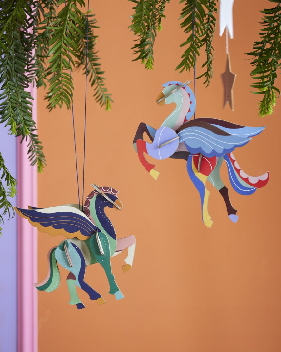 2 Studio Roof DIY card Pegasus Christmas tree decorations hanging in front of an orange background