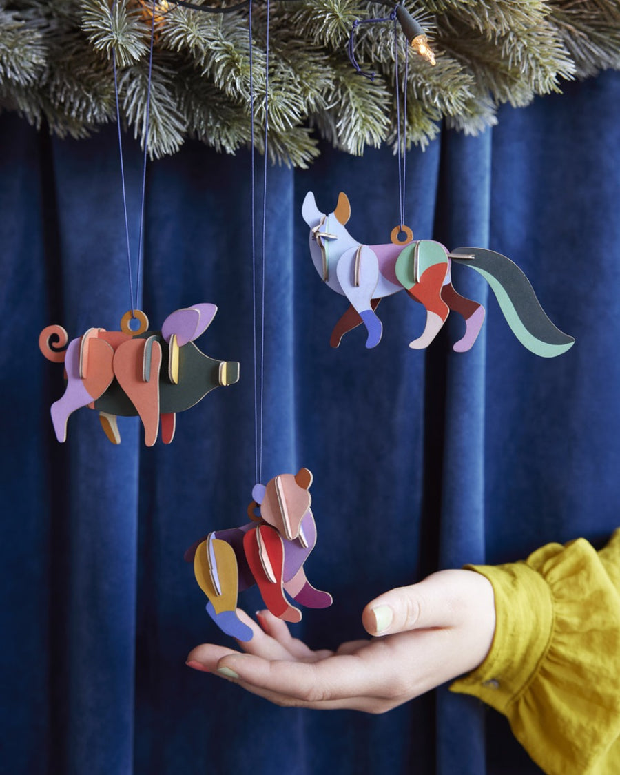 Close up of a hang reaching out to touch a Studio Roof plastic-free animal hanging decoration