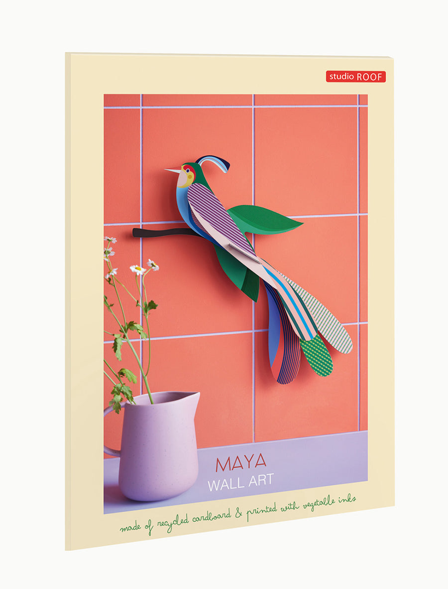 Studio Roof Maya bird of Paradise sat on a dark brown tree branch with green leaves