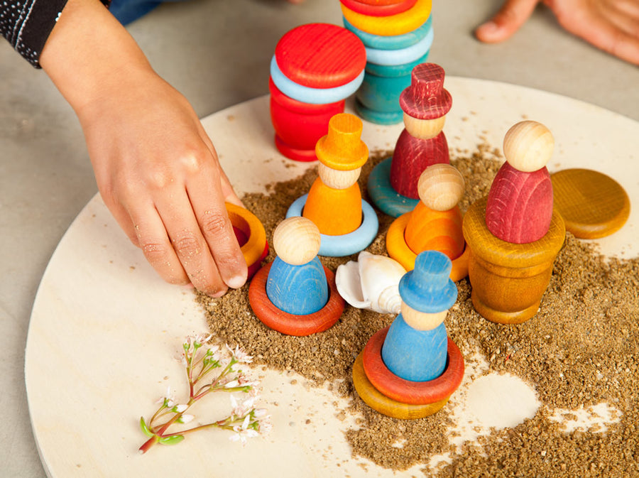 being played with by a child. Sand and wooden play tray background.