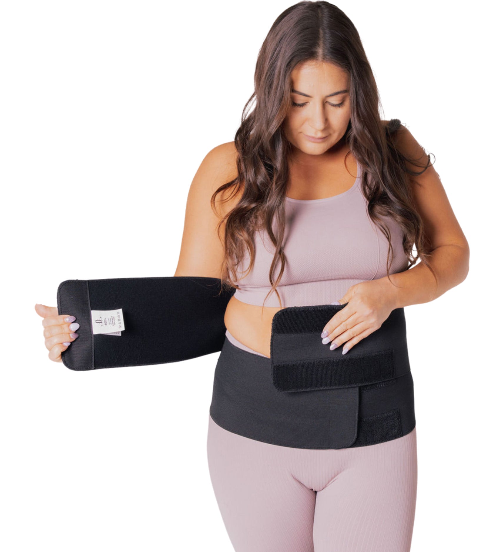 A person wearing a pink outfit, showing how to put on the Lola & Lykke Core Restore Postpartum Belly Band