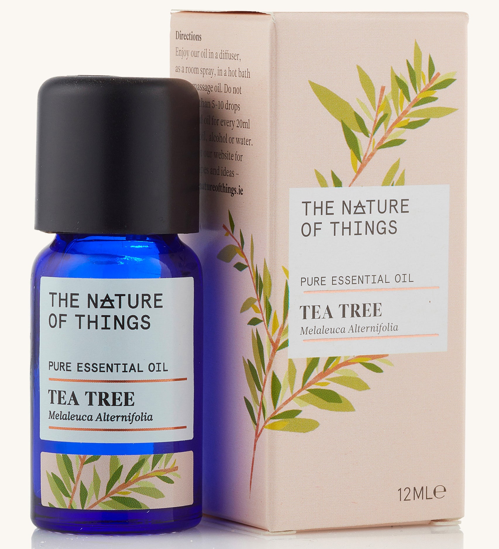 Tea tree pure essential oil in a blue glass bottle in front of a decorative pink cardboard box.