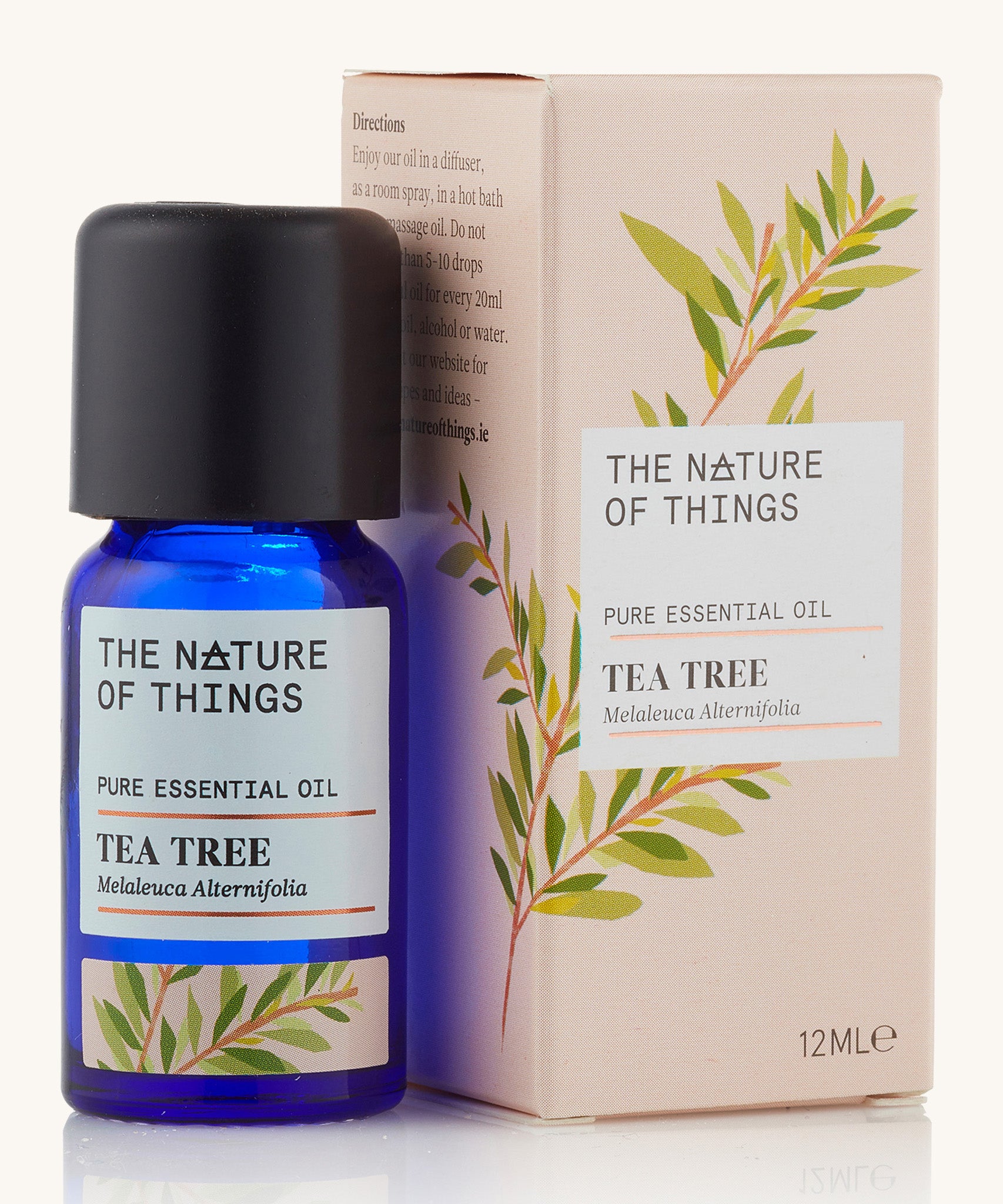 Tea tree pure essential oil in a blue glass bottle in front of a decorative pink cardboard box.