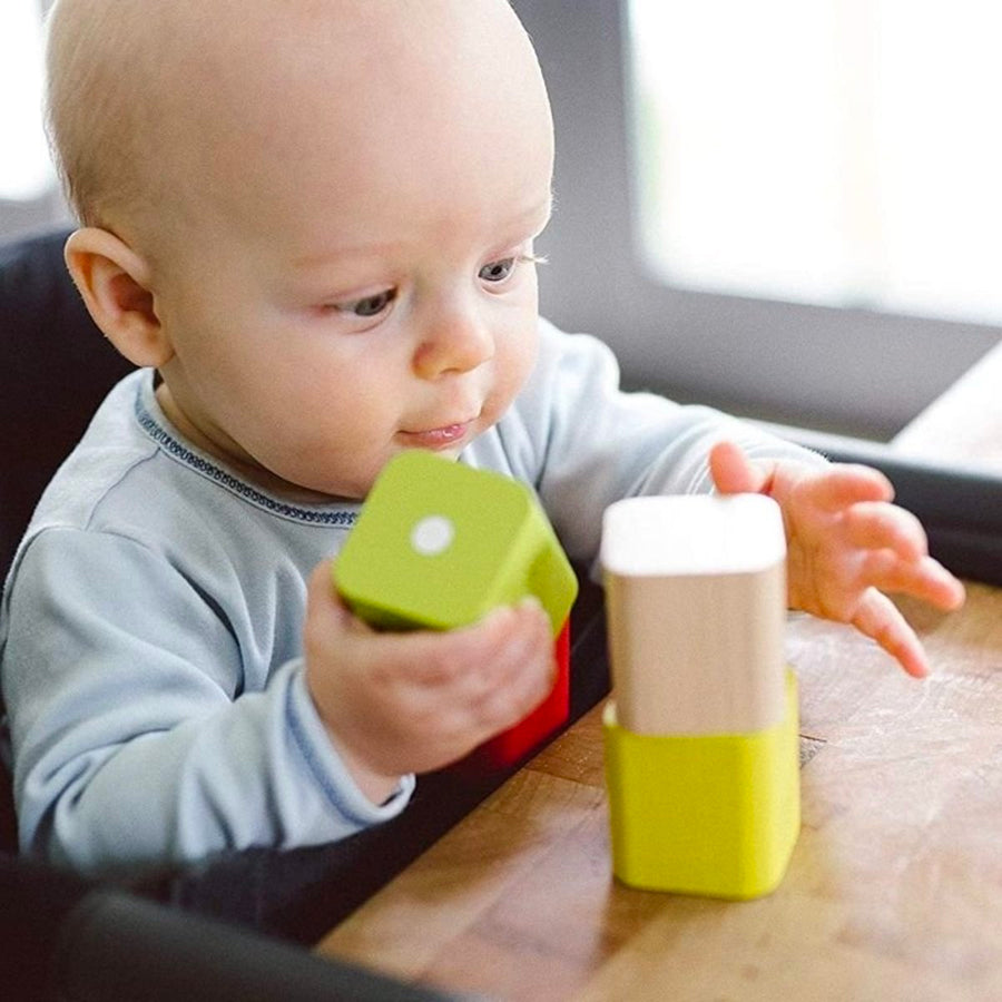 A baby stacking Tegu Baby's First Building Blocks at a table.