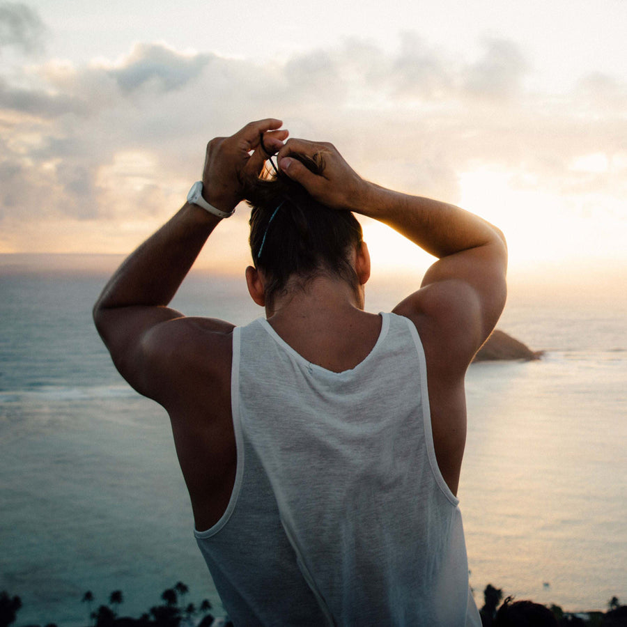 Man putting his hair into a Terra Ties biodegradable black hair band while looking out at the sea