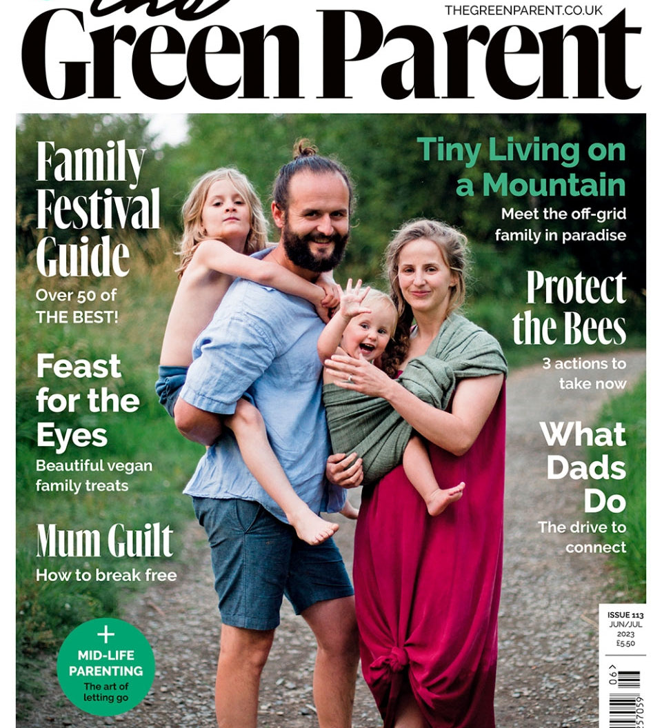 Green parent magazine cover featuring a mother using a sling to carry a young child and a father giving an older child a piggy back.