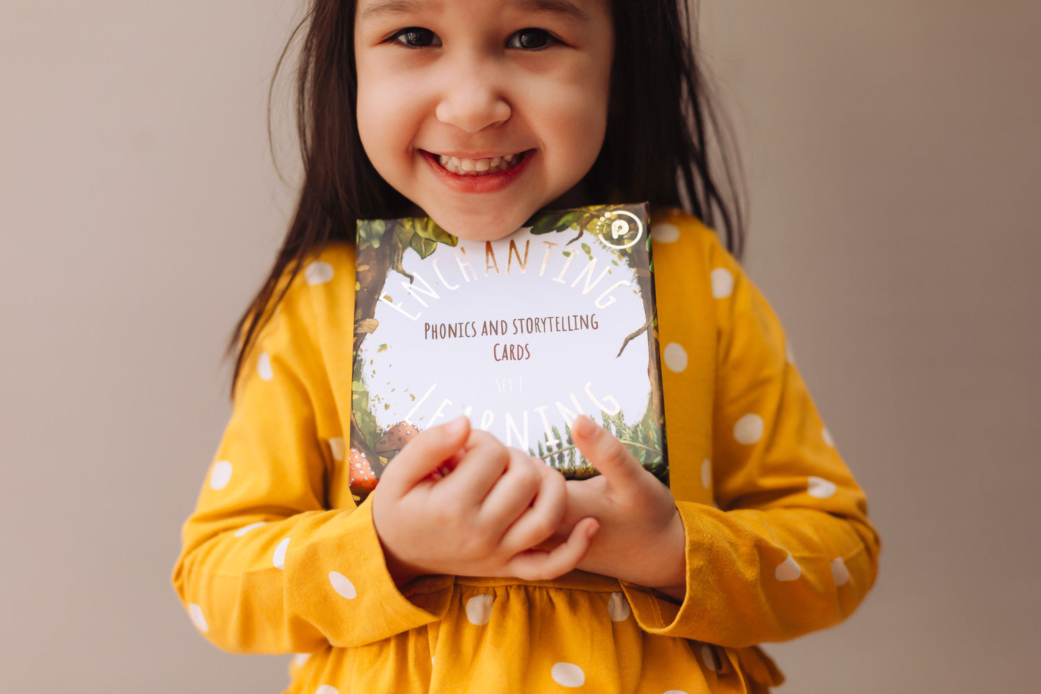 Child holding a box of The Phive Enchanting Learning Phonics & Storytelling Cards - Set 1