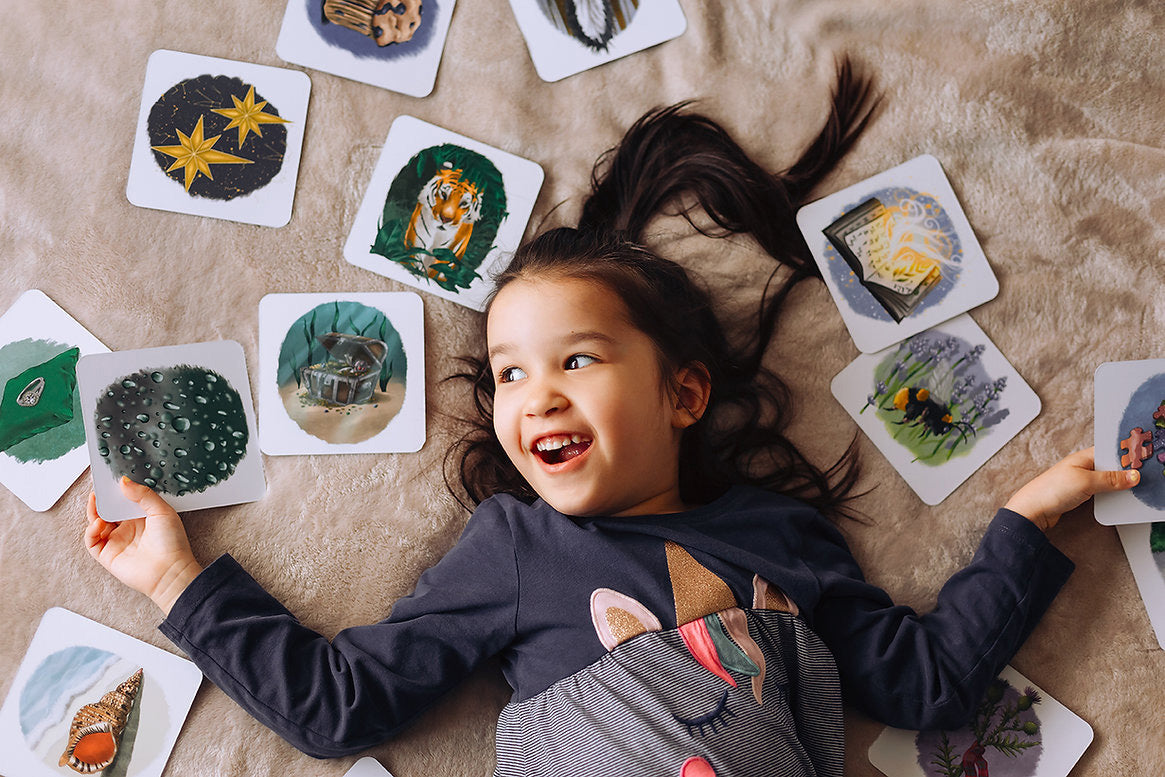 Child lying down surrounded by cards from the The Phive Enchanting Learning Phonics & Storytelling Cards  Set 2