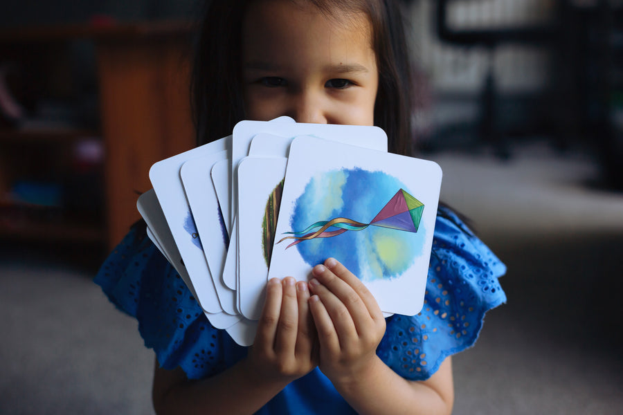 Child holding the cards from the The Phive Enchanting Learning Phonics & Storytelling Cards - Set 3 in a fan front of their face