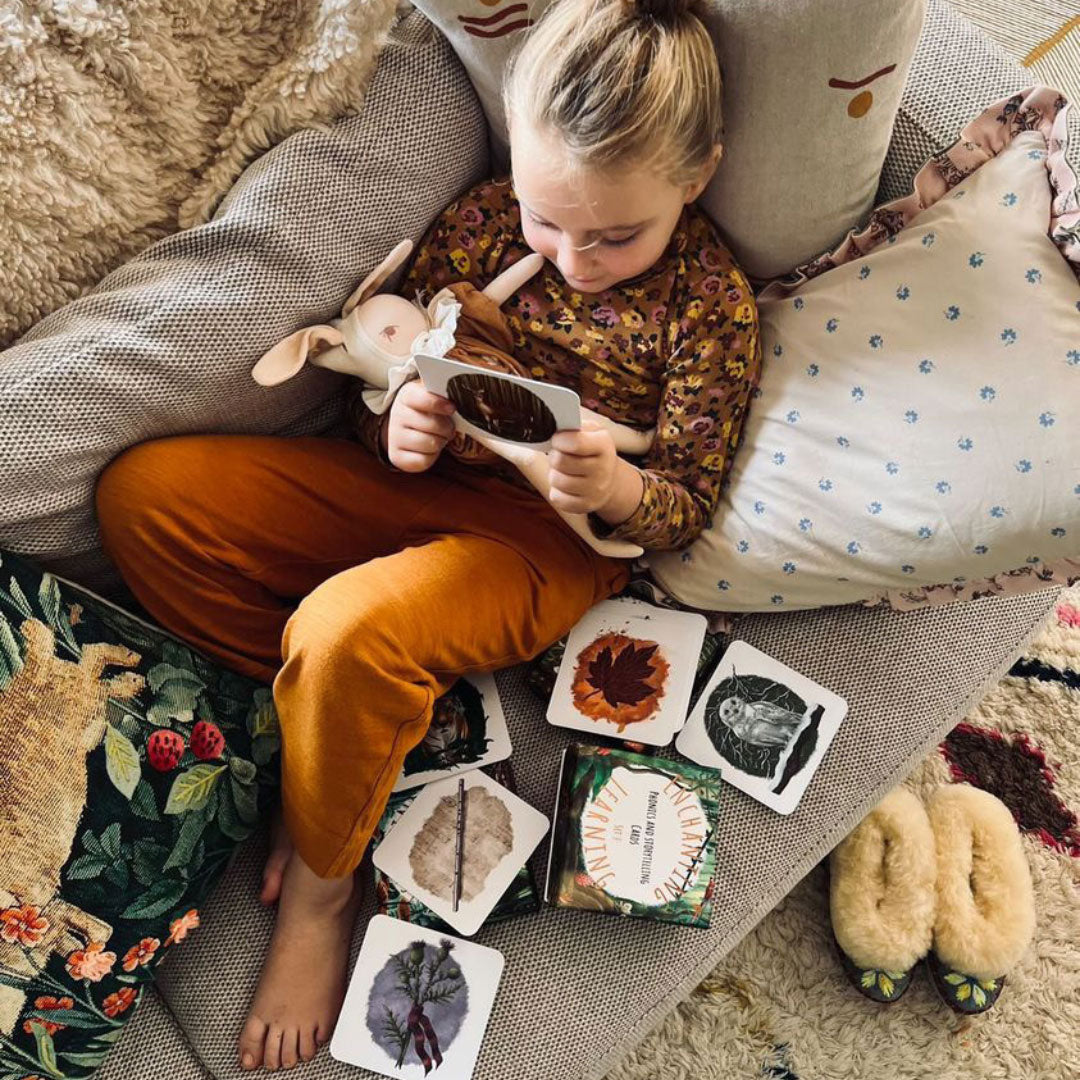 Child sitting on a sofa surrounded by cushions