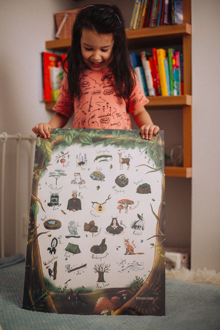 A child holding up the The Phive Enchanting Woodland Alphabet Print