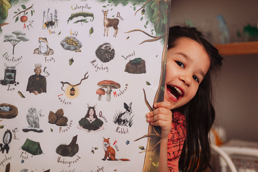 A close up of a child holding The Phive Enchanting Woodland Alphabet Print