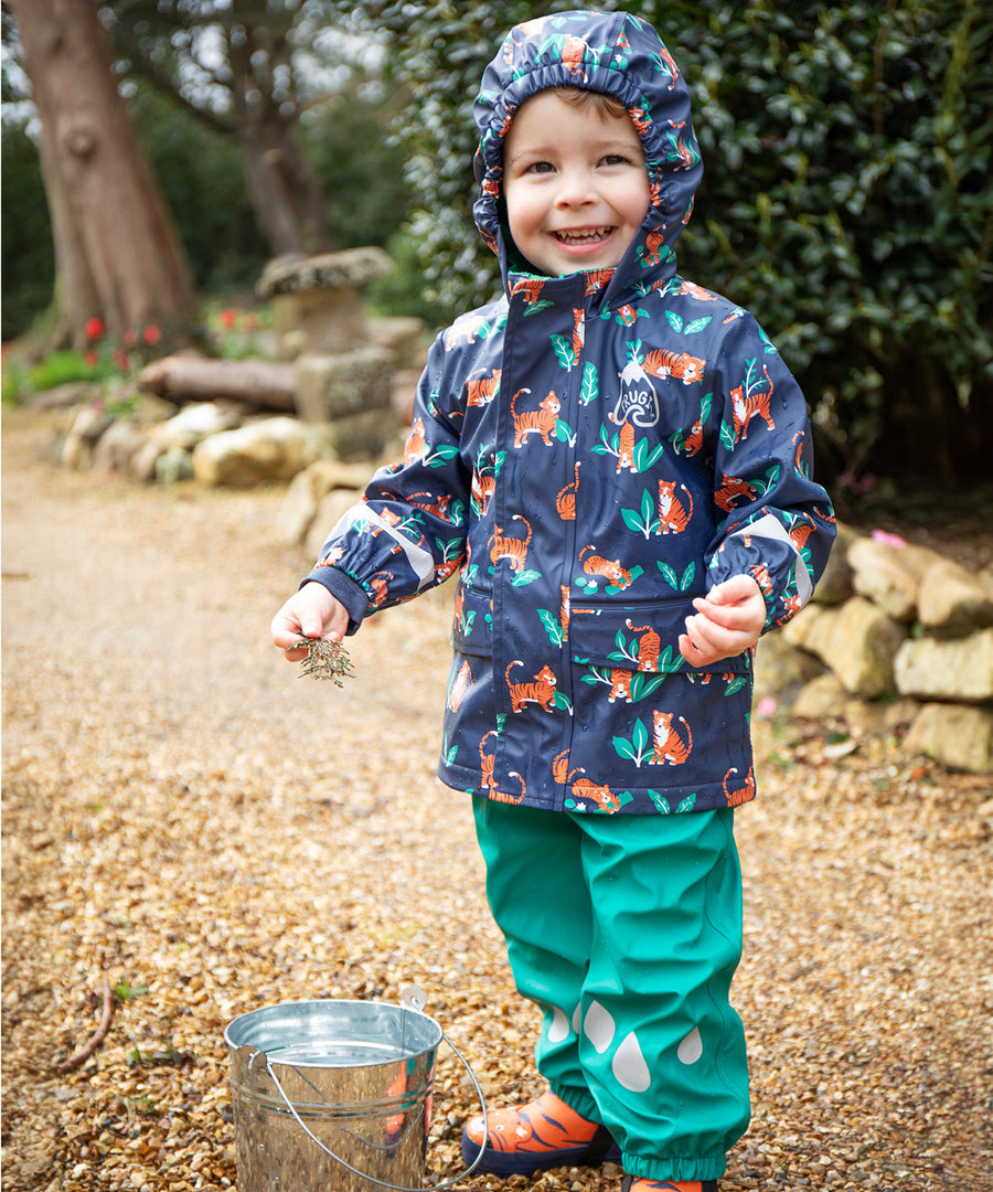 Two children playing with a stick in a stream. The child at the front is wearing the Frugi Children's Puddle Buster Trousers - Iguana Turquoise