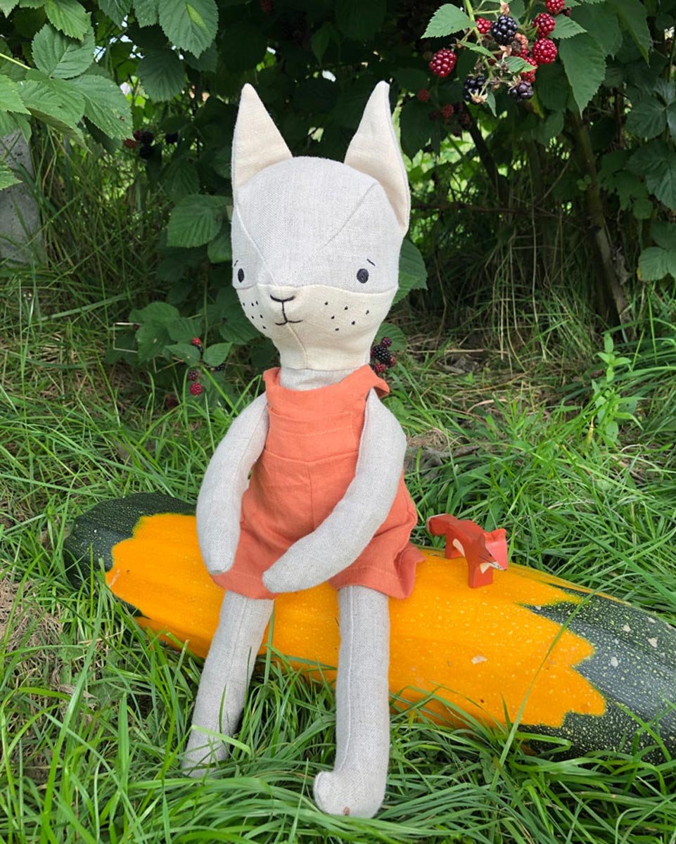 Close up of the Tobe hempions fox toy in a small tree surrounded by red berries