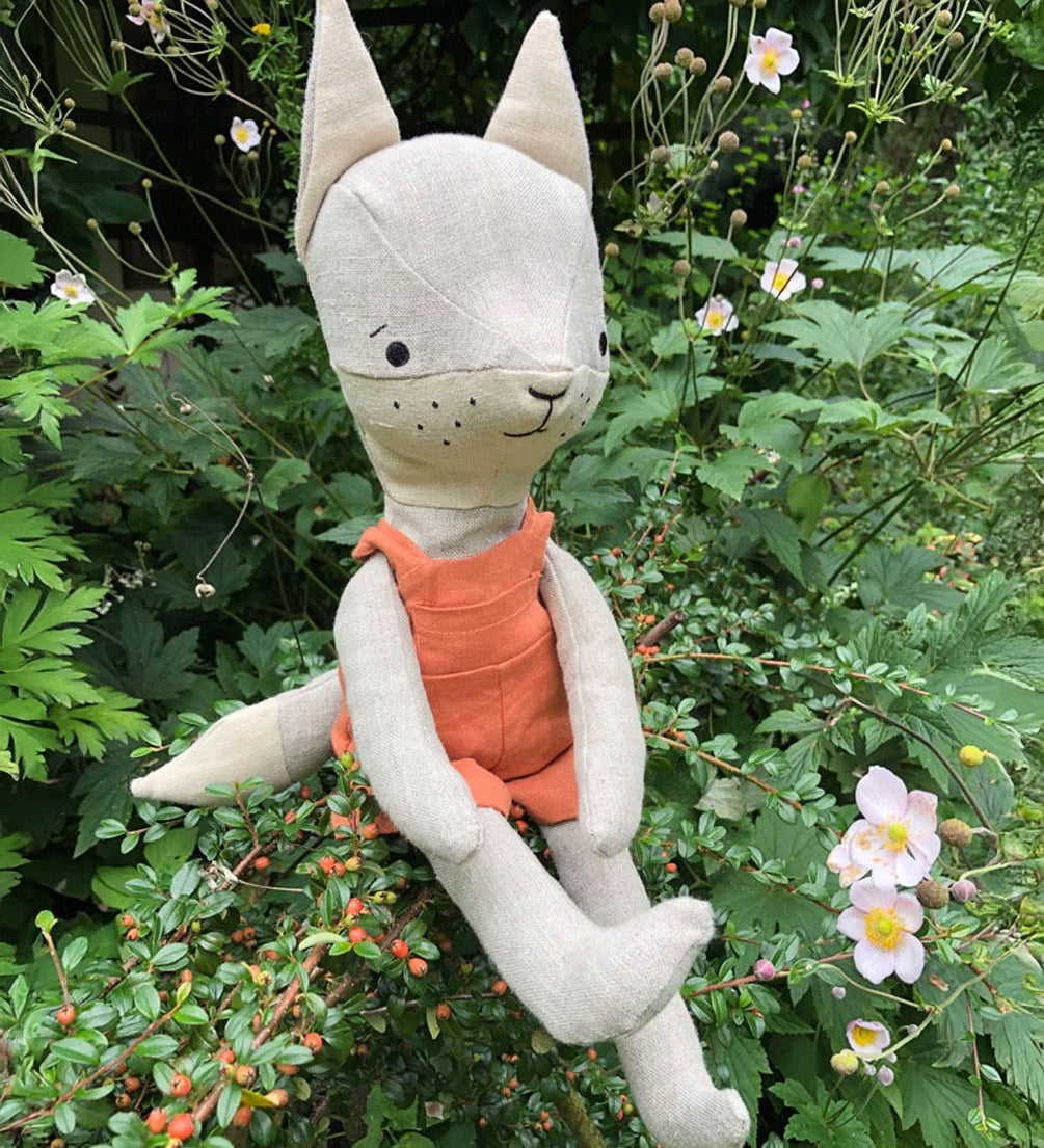 Tobe the hempions fox toy placed on greenery outdoors. 