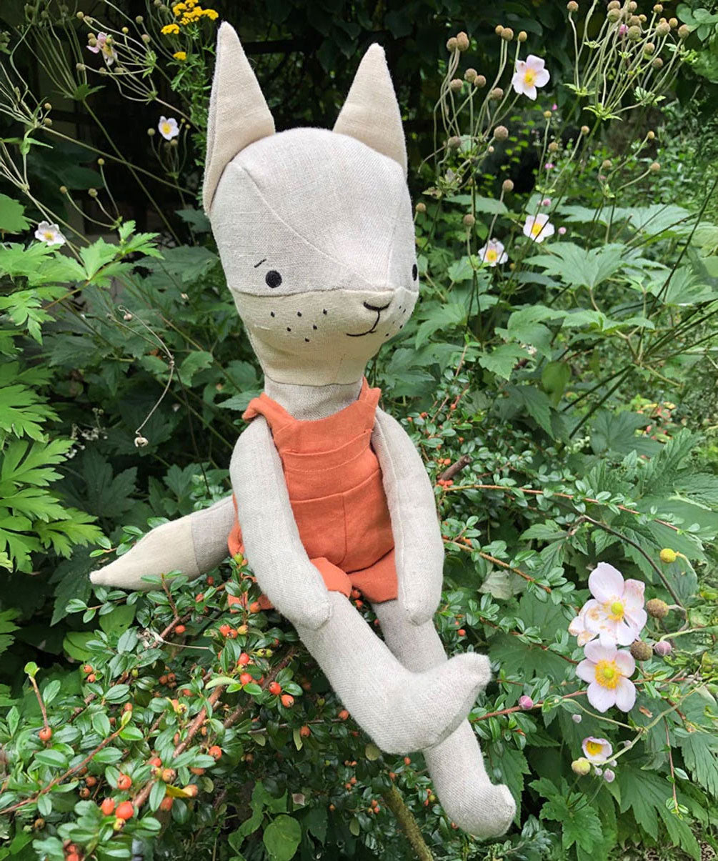 Tobe the hempions fox toy placed on greenery outdoors. 