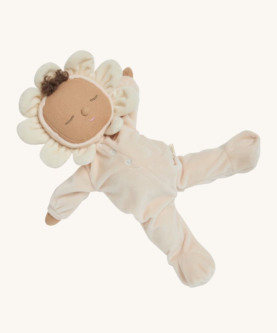 A light cream dozy dinkum doll lying down on a cream background.