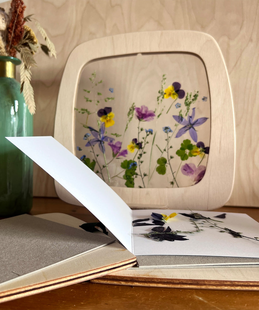 A person gluing their dried flowers onto a silhouette piece