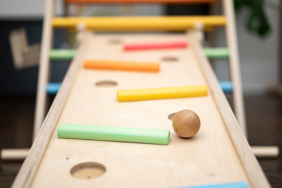 Close up of wooden balls rolling down a ball run made with the Triclimb wooden Miri slide and pastel Miri sticks