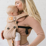 Close up of woman kissing a baby in a Tula explore front facing baby carrier