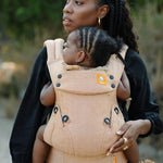 Close up of woman holding a baby in a Tula beige herringbone explore baby carrier