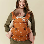 Front view of a woman carrying her baby on her front in the Tula Ergonomic Multi-Position Explore Baby Carrier 7-45lbs in Sedonia.