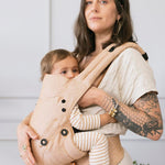 Woman carrying a baby in a Tula explore beige baby carrier