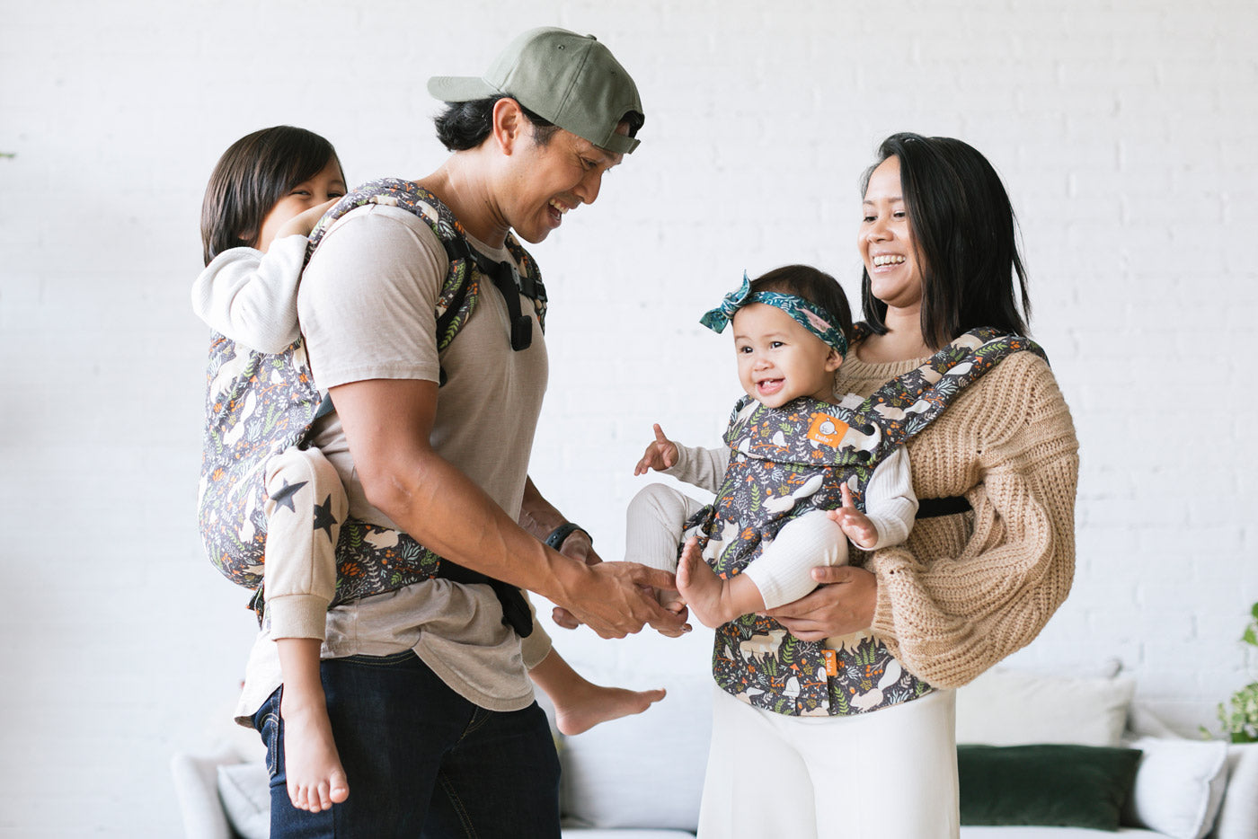 Woman stood carrying a baby on her front in the Tula soft structured fox tail baby carrier