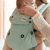 A baby is happily sat up in the Tula Explore Carrier