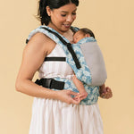 Adult carrying a baby with the Tula Free To Grow Paradise print Baby Carrier