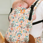 Close up of a baby sleeping in a Tula white woodland print free to grow baby carrier