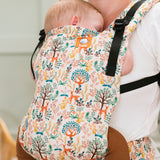 Close up of a baby sleeping in a Tula white woodland print free to grow baby carrier