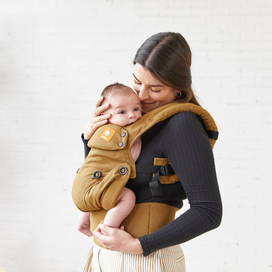 A female with baby in the The Tula Hemp Explorer Baby Carrier in Olivine