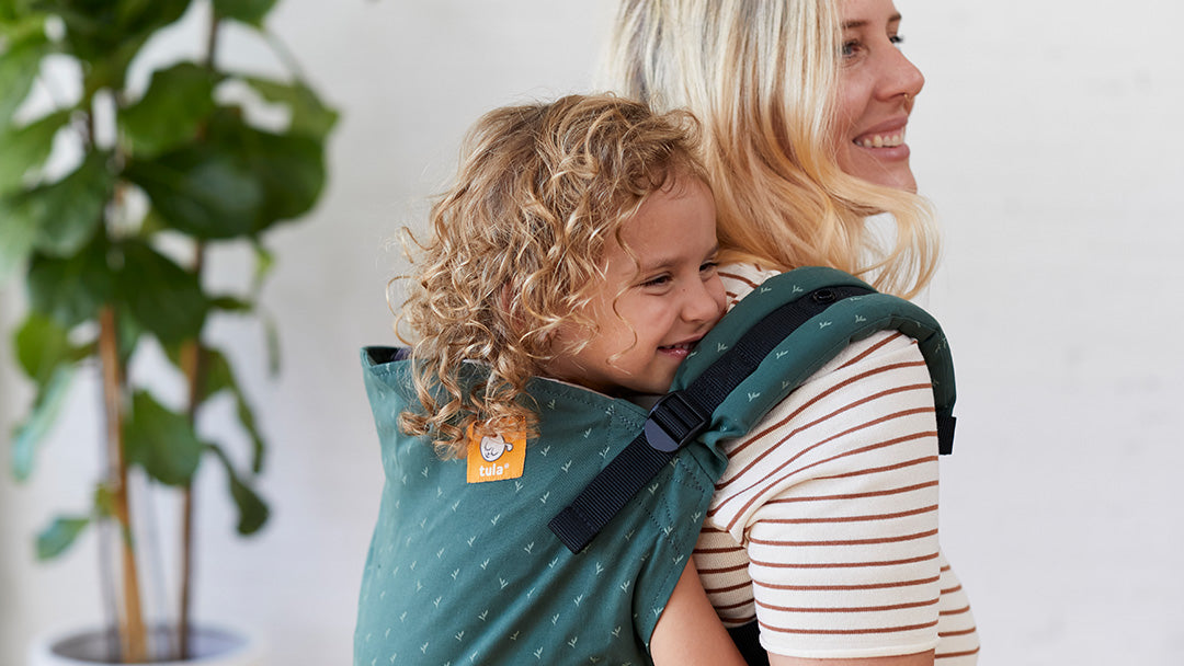 Woman carrying a toddler in a Tula toddler baby carrier