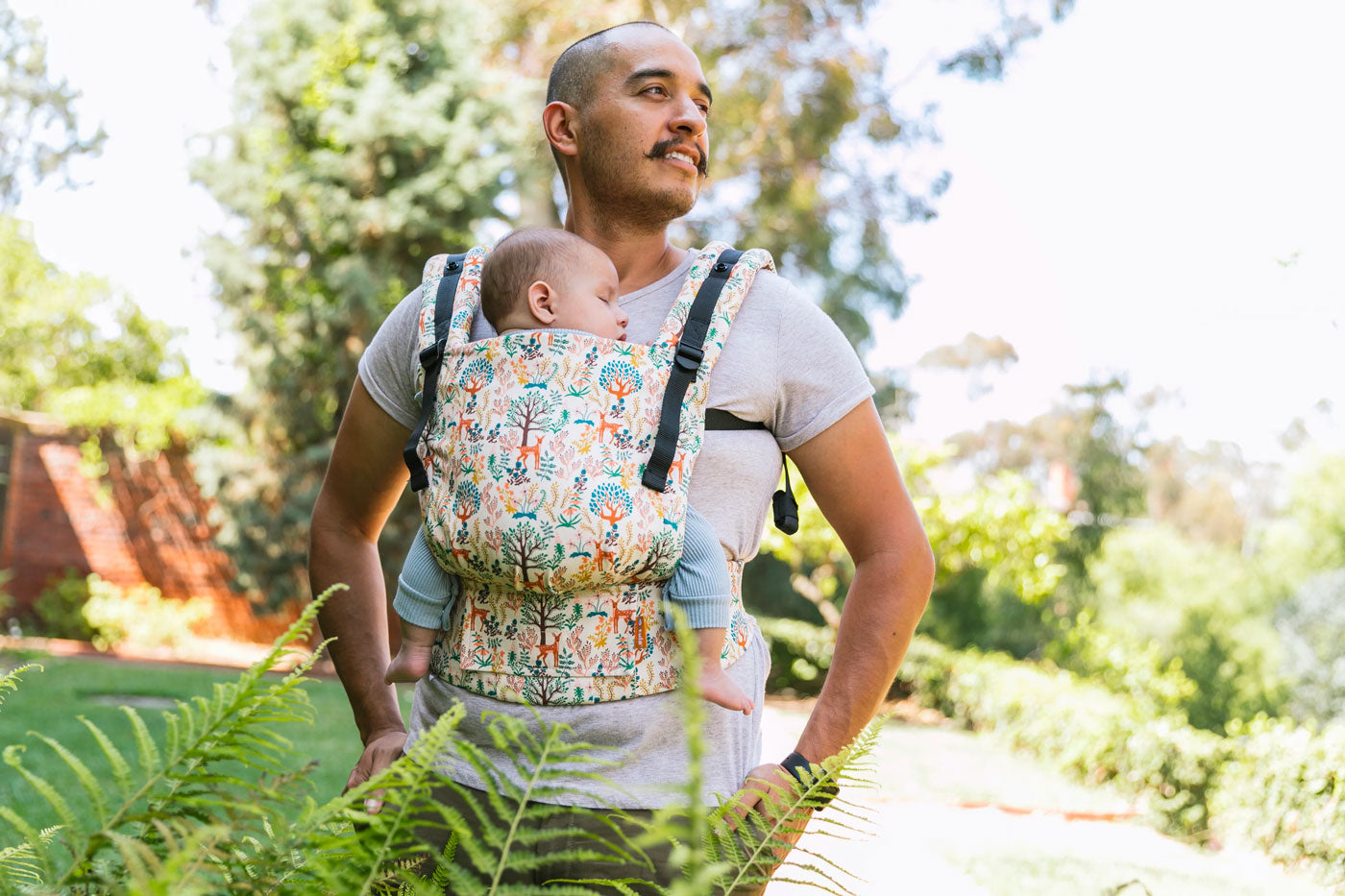 Close up of man in a garden with a baby inside a Tula soft structured FTG baby carrier